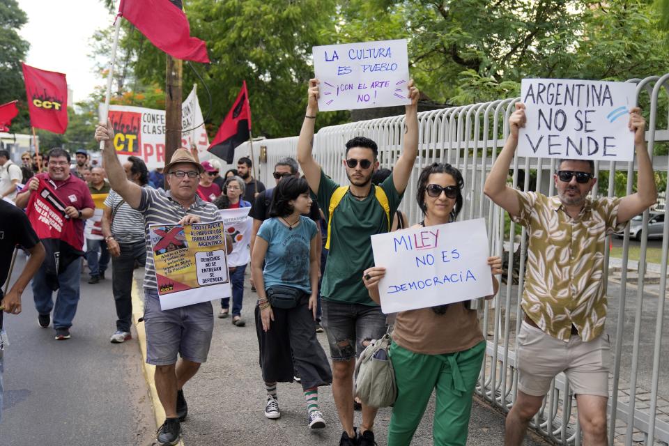 People march in support of a national strike in Argentina against President Javier Milei, outside Argentina's embassy in Asuncion, Paraguay, Wednesday, Jan. 24, 2024. The signs read in Spanish "Miley is is not democracy," with a play on the spelling of "ley" or "law" in Melei's last name, and "Argentina is not for sale." (AP Photo/Jorge Saenz)