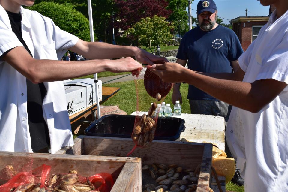 Cooks load clams into mesh bags to prepare them for steaming at a clambake at East Providence's Squantum Association.