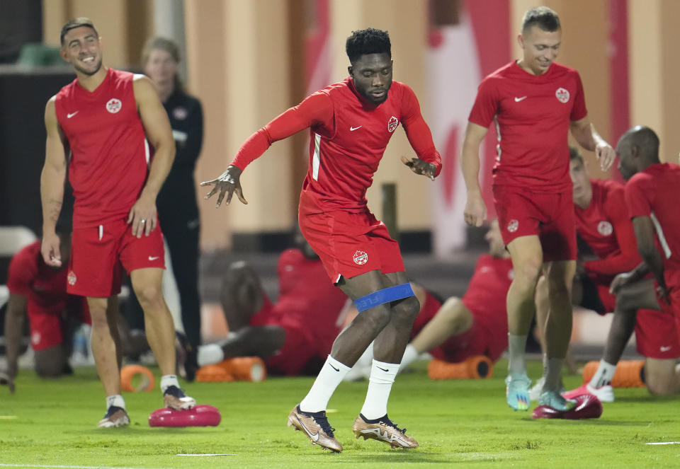 Canada forward Alphonso Davies, center, warms up during practice at the World Cup soccer tournament in Doha, Qatar, Tuesday, Nov. 22, 2022. (Nathan Denette/The Canadian Press via AP)