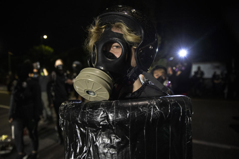 A protester wearing a gas mask is seen during the nightly protests at a Portland police precinct on Sunday, Aug. 30, 2020 in Portland, Ore. Oregon State Police will return to Portland to help local authorities after the fatal shooting of a man following clashes between President Donald Trump supporters and counter-protesters that led to an argument between the president and the city's mayor over who was to blame for the violence. (AP Photo/Paula Bronstein)