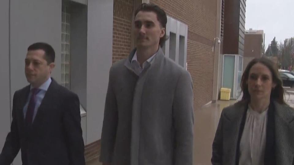 Canadian professional ice hockey player Alex Formenton, centre, walks into police headquarters in London, Ont., on Sunday.