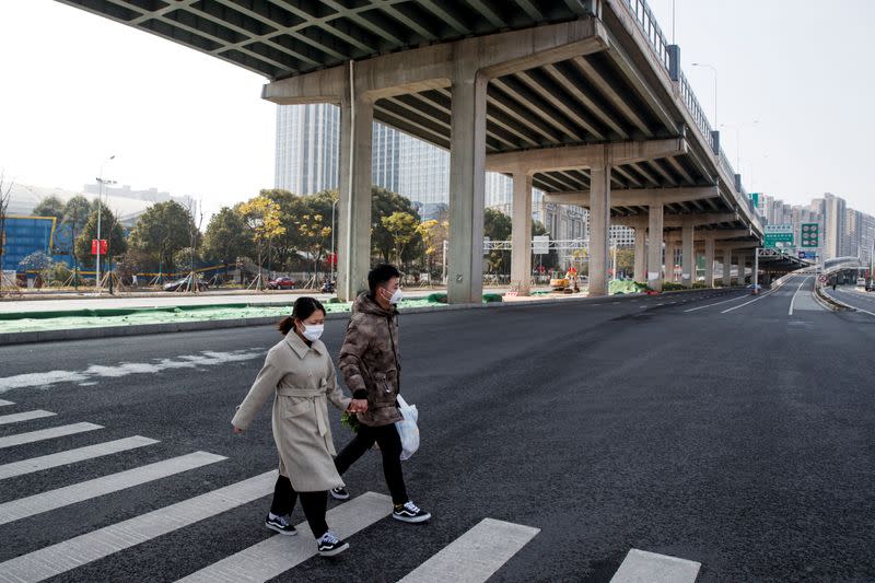 La gente usa máscaras faciales al cruzar una calle principal vacía en Changsha, provincia de Hunan, China, mientras el país es golpeado por un brote de un nuevo coronavirus, el 29 de enero de 2020