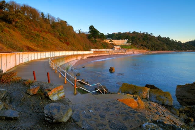 Looking along the promenade of Meadfoot Beach in Torquay in South Devon England at sunrise