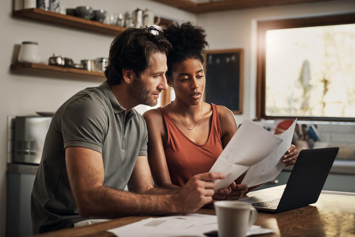 cropped shot of an affectionate young couple going through paperwork while doing their budget at home