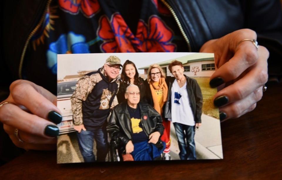 Minnesota Lt. Gov. Peggy Flanagan holds a photo of herself, second from right, her father Marvin Manypenny, front center, Minnesota Gov. Tim Walz, left, and family in 2018 on White Earth Nation tribal land.