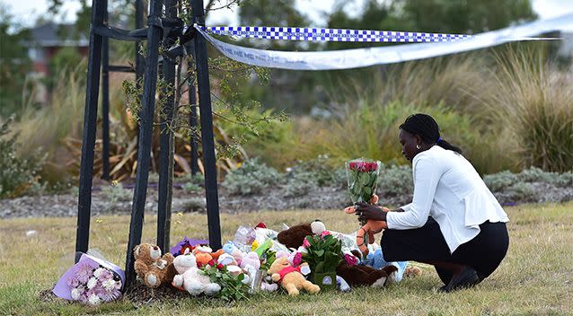 A woman places flowers at a makeshift shrine at the scene where the 4WD was submerged in Lake Gladman. Photo: AAP