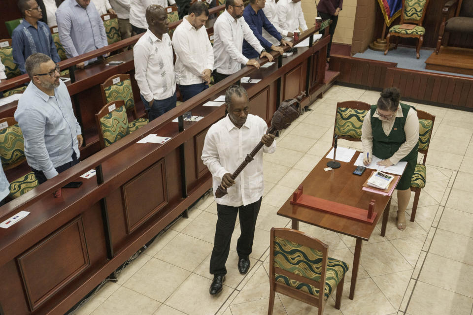 Un miembro del Senado con la escultura de madera llamada El Mazo de la Asamblea Nacional de Belice, para colocarlo en el centro de la habitación y dar comienzo a la sesión, durante la visita de la presidenta de Taiwán, Tsai Ing-wen, en Belmopán, Belice, el lunes 3 de abril de 2023. Tsai está de visita oficial de tres días en Belice. (AP Foto/Moiseés Castillo)