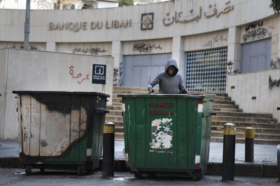 A man scavenges in a dumpster for valuables and metal cans that can be resold, in Beirut, Lebanon, Sunday, Jan. 16, 2022. As Lebanon faces one of the world’s worst financial crises in modern history, now even its trash has become a commodity fought over in the street. (AP Photo/Lujain Jo)