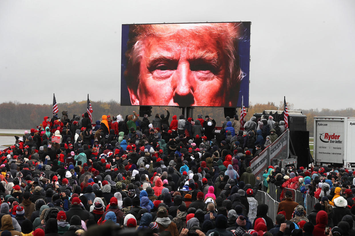 Supporters watch a video of President Donald Trump while waiting for his arrival at a campaign rally at Capital Region International Airport in Lansing, Mich. on Oct. 27, 2020.