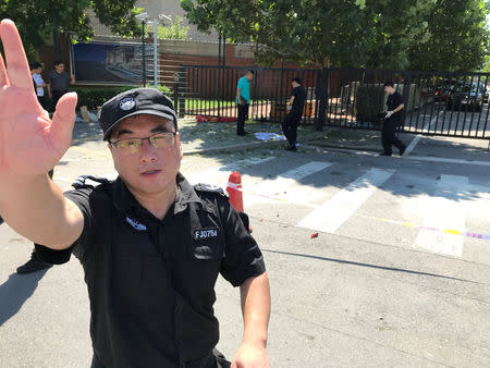 A security personnel gestures near the U.S. embassy in Beijing, China July 26, 2018. REUTERS/ Thomas Peter