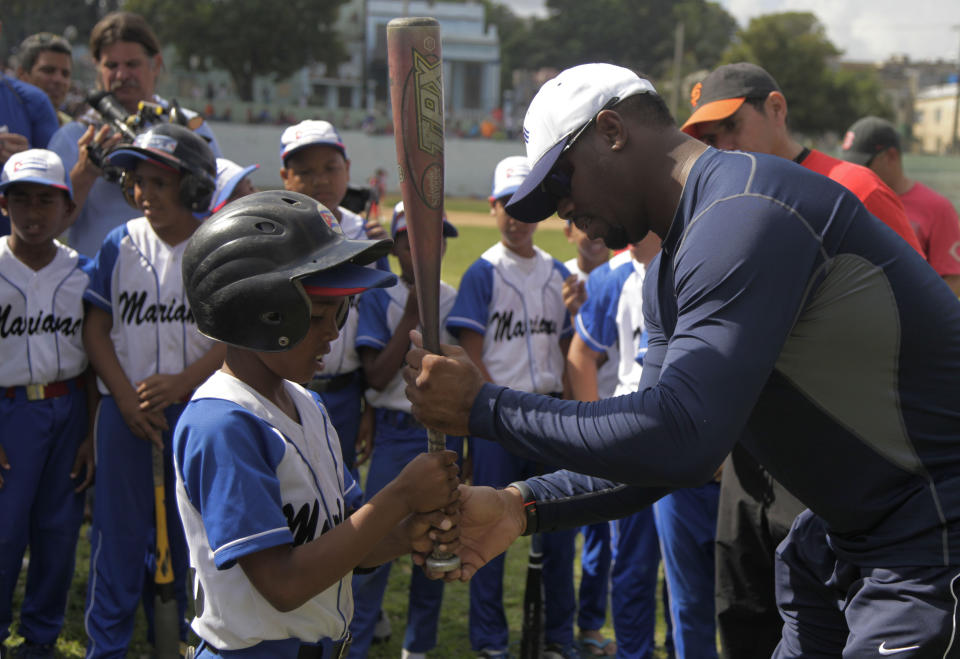 CAPTION ADDITION TO INCLUDE DAY AND DATE - Major League Baseball's Hall of Famer Ken Griffey Jr., right, shows a group of young ballplayers how to grip a bat properly during a baseball clinic in Havana, Cuba, Sunday, Feb. 9, 2014. Griffey and Barry Larkin are visiting as part of a sports diplomacy program that aims to foster personal ties between the United States and Cuba. During the five-day visit they’re holding baseball clinics for little-leaguers and seniors, talking ‘pelota’ with Cuban fans and taking in a game featuring Havana's powerhouse ball club. (AP Photo/Franklin Reyes)