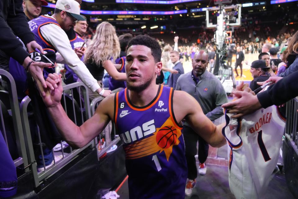 Phoenix Suns guard Devin Booker high-fives fans after the team's 100-93 win over the Denver Nuggets at Footprint Center in Phoenix on March 31, 2023.