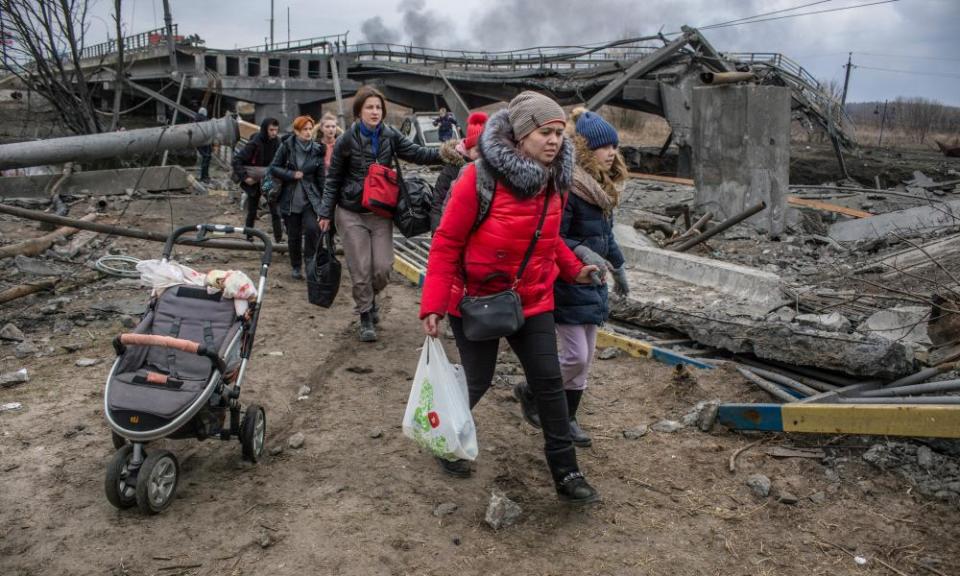 Civilians cross amid rubble of a damaged bridge in Irpin