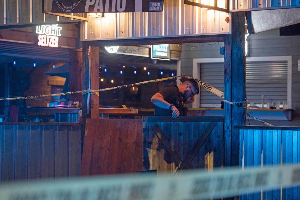 A law enforcement officer goes under a crime scene tape surrounding The Scratch Kitchen restaurant after a shooting during a Cinco de Mayo late Friday, May 5, 2023, in Ocean Springs, Miss.