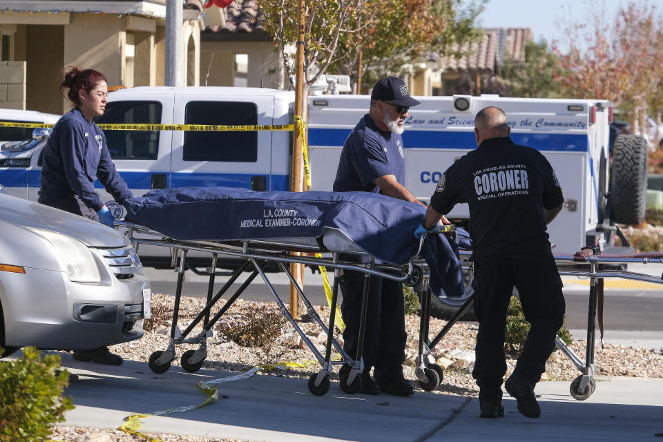 Los Angeles County Coroner officials remove a body from a home where five bodies were found dead, in the city of Lancaster in the high desert Antelope Valley north of Los Angeles, Monday, Nov. 29, 2021. A Los Angeles County Sheriff's Department statement says deputies found a woman, a girl and three boys with gunshot wounds and paramedics pronounced them dead at the scene. The department says the children's father showed up at the Lancaster sheriff's station and was arrested on suspicion of five murders after being interviewed by detectives. (AP Photo/Ringo H.W. Chiu)