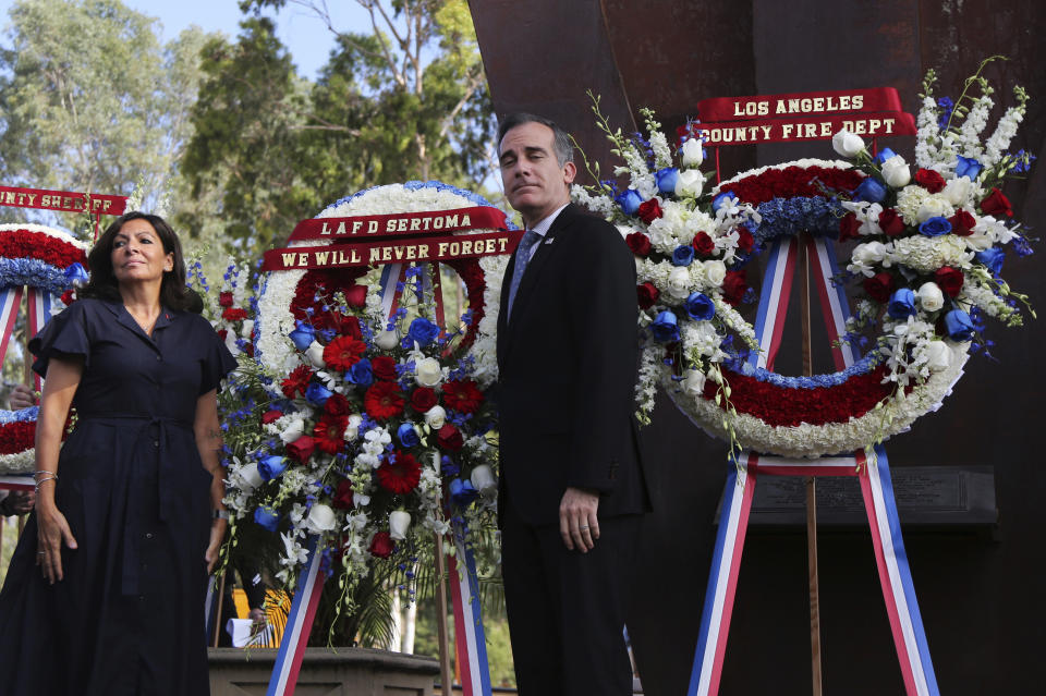 Paris Mayor Anne Hidalgo and Los Angeles Mayor Eric Garcetti pose with wreaths during a ceremony marking the 17th anniversary of the Sept. 11, 2001 terrorist attacks on the United States, at the Los Angeles Fire Department's training center Tuesday, Sept. 11, 2018. In the right background is the largest fragment of the World Trade Center outside New York. (AP Photo/Reed Saxon)