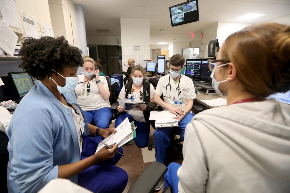 Vanessa Jean-Baptiste, left, a registered nurse in the intensive care unit at Northern Westchester Hospital in Mount Kisco, reviews patient information with fellow nurses at the beginning of their 7 p.m. to 7 a.m. shift on Feb. 28, 2022. Two years into the COVID-19 pandemic, Jean-Baptiste continues to work three overnight shifts a week in the hospital's ICU. With Jean-Baptiste are, clockwise from left: Nurses Kate D'Angelone, Selvija Dedushaj, Justin O'Rourke and Victoria Cotto.