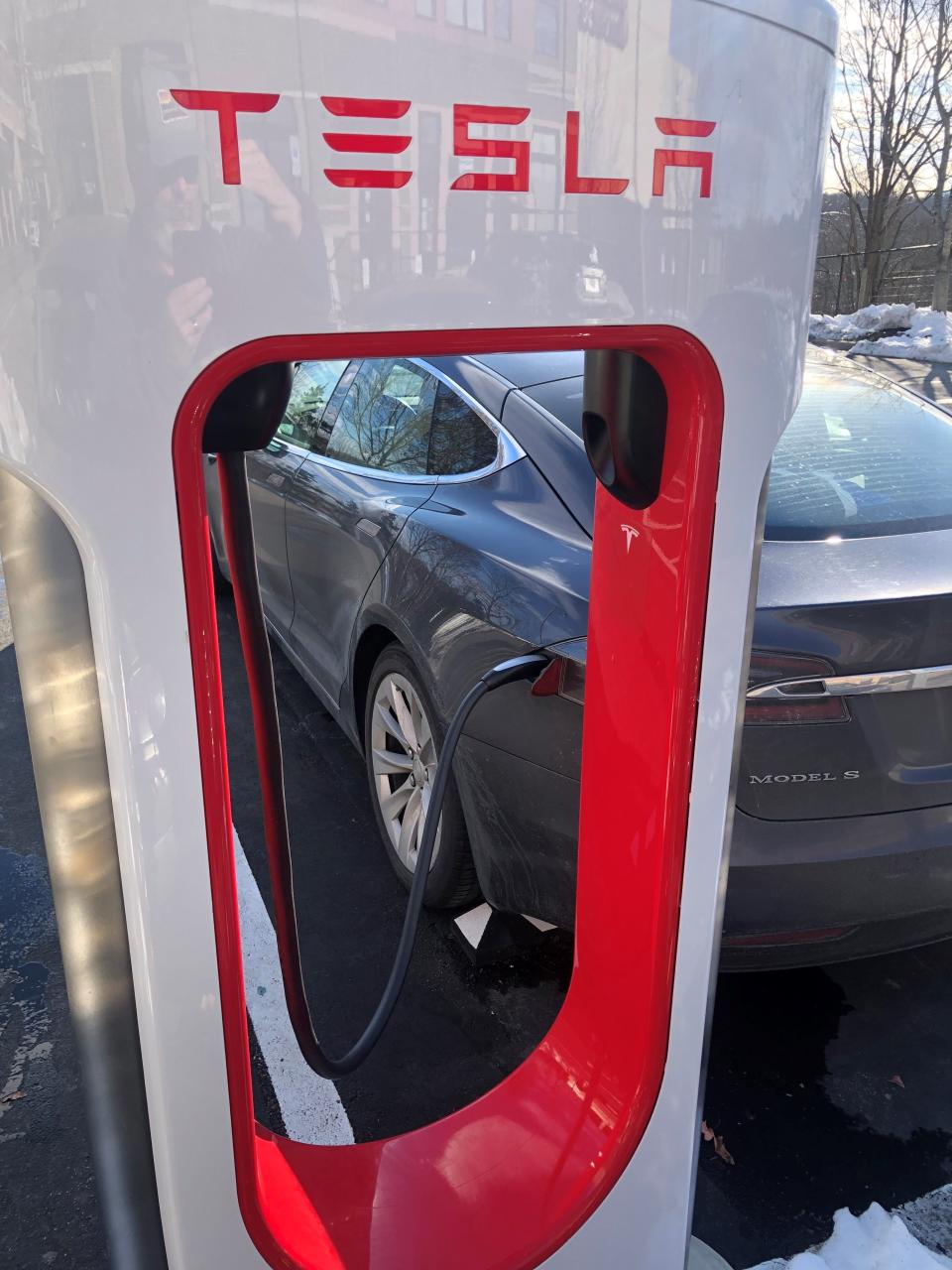 A Tesla takes a charge from a new charging station in Biltmore Park. Signs in the lot say the stations are for Tesla vehicle charging only.