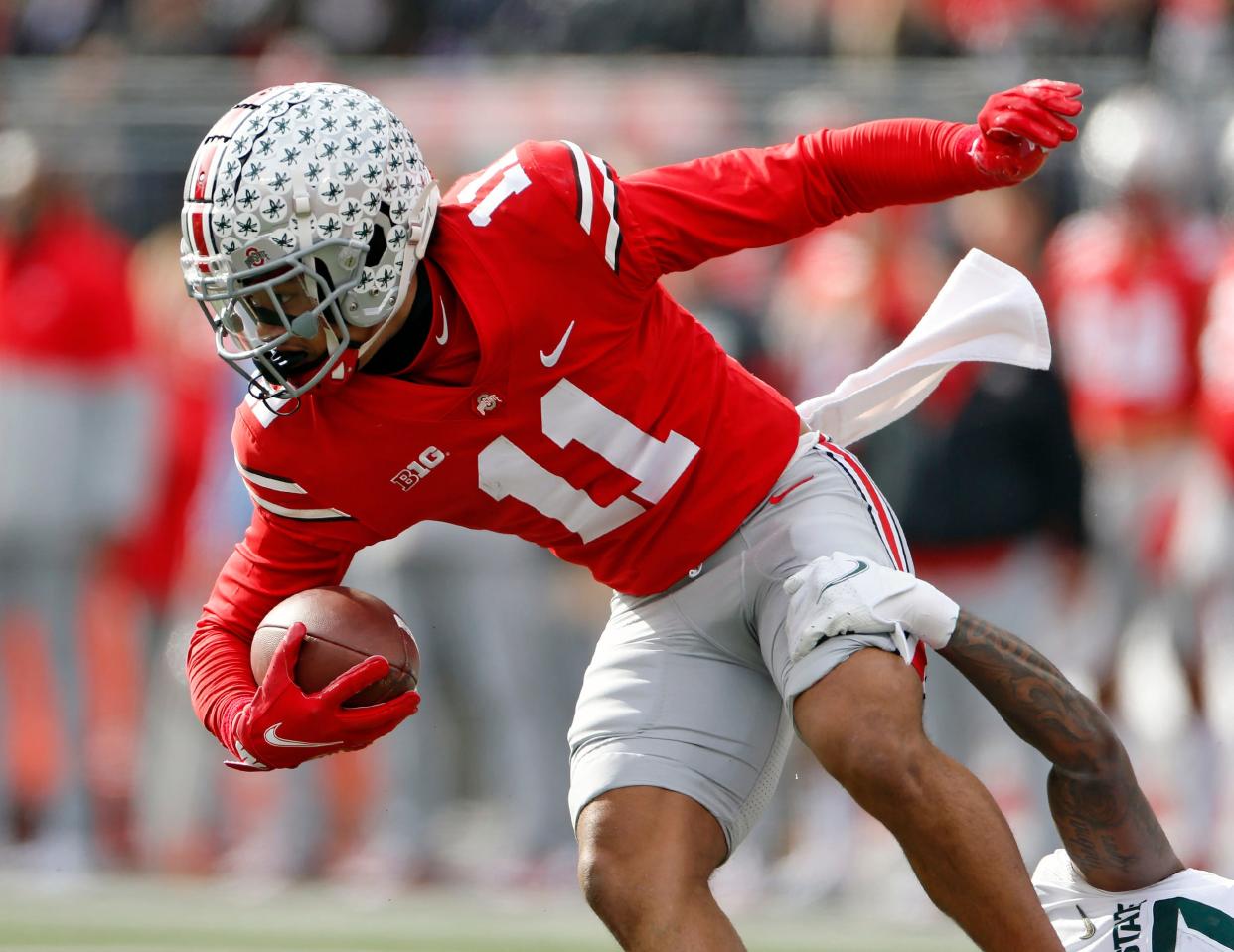 Ohio State Buckeyes wide receiver Jaxon Smith-Njigba (11) gets pulled down by Michigan State Spartans wide receiver Tre Mosley (17) on a punt return in the first quarter during their NCAA College football game at Ohio Stadium in Columbus, Ohio on November 20, 2021. 