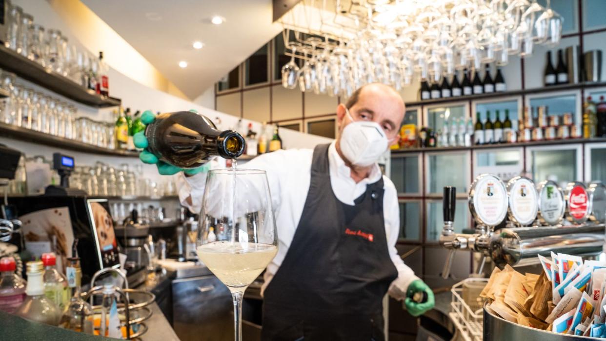 Ein Barmann mit Atemschutzmaske schenkt in Bozen ein Glas Wein ein. (Archivbild)