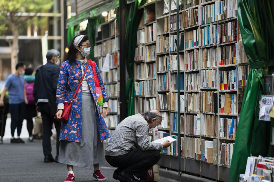 People wearing face masks shop around at a secondhand book store in Tokyo on Thursday, Oct. 29, 2020. (AP Photo/Hiro Komae)