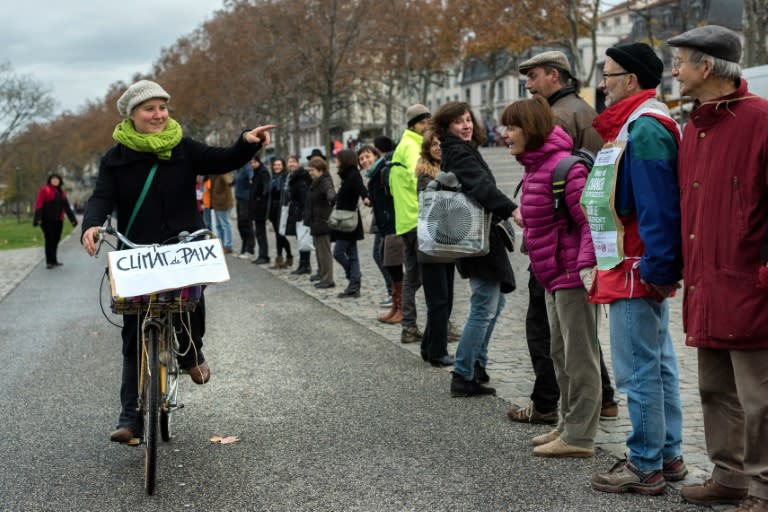 A woman rides a bicycle with a placard reading "Climate for Peace" alongside one of the many human chains formed across cities in France on November 29, 2015