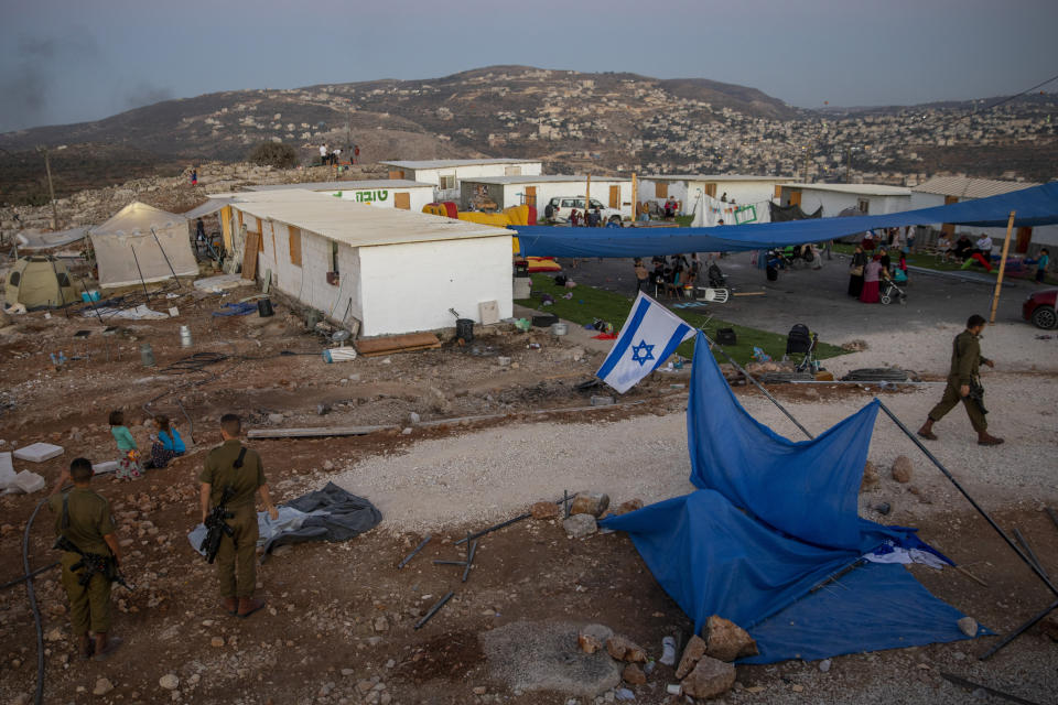 FILE - Israeli settlers and soldiers gather at the recently established wildcat outpost of Eviatar near the West Bank city of Nablus, Thursday, July 1, 2021. Israel's attorney general has okayed a deal between the government and West Bank settlers that would retroactively authorize the outpost established without official approval, Israeli media reported Wednesday, Feb. 2, 2022. (AP Photo/Oded Balilty, File)