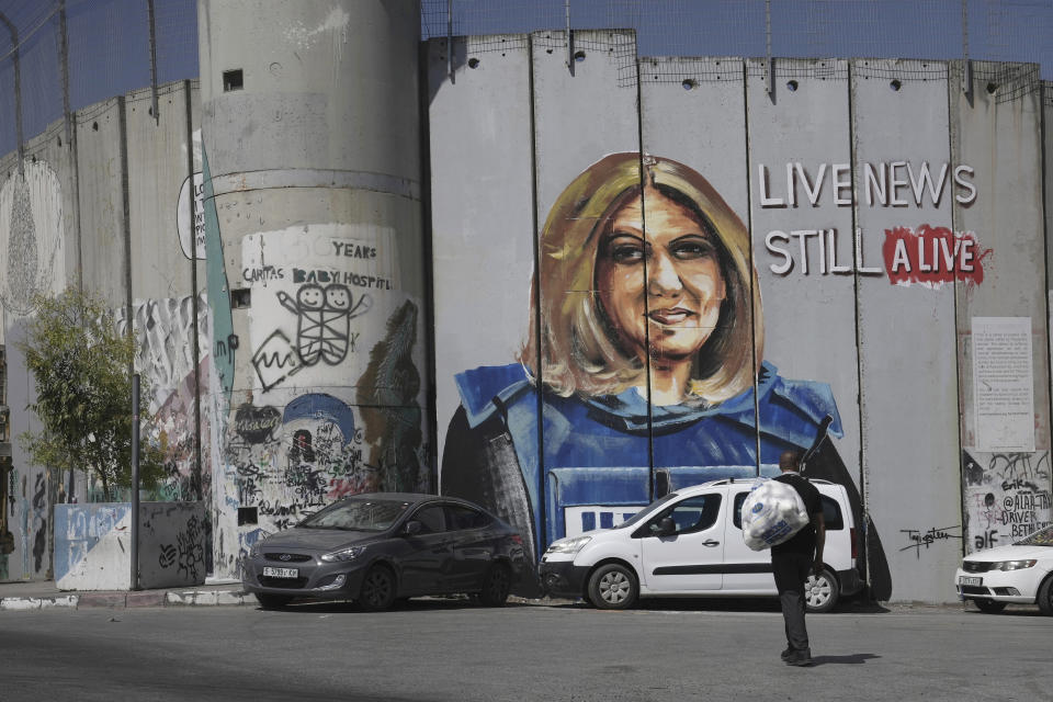 A man walks near a mural depicting slain Palestinian American journalist Shireen Abu Akleh, on Israel's controversial separation barrier in the West Bank city of Bethlehem, Wednesday, July 6, 2022. The mural by Palestinian artist Taqi Spateen appeared early Wednesday, days ahead of a visit by U.S. President Joe Biden. (AP Photo/ Mahmoud Illean)