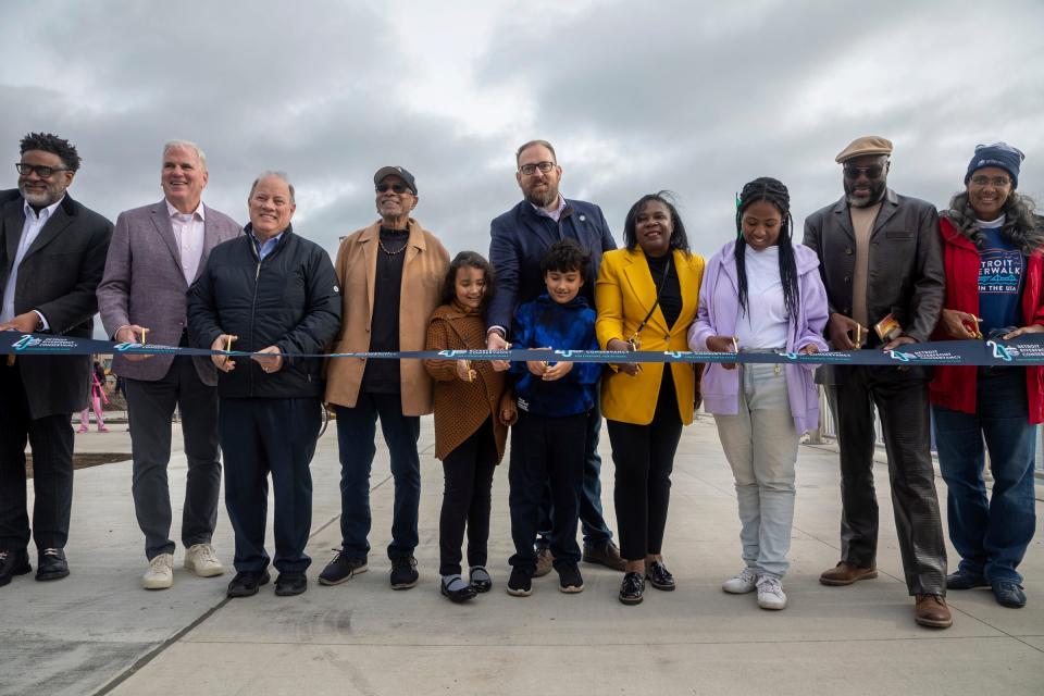 Mayor Mike Duggan, third from the left, prepares to cut the ribbon alongside others during the Uniroyal Promenade ribbon-cutting ceremony on DetroitÕs Riverwalk in Detroit on Saturday, Oct. 21, 2023. The new Uniroyal Promenade completes the 3.5 mile-long Riverwalk and provides access to Belle Isle.