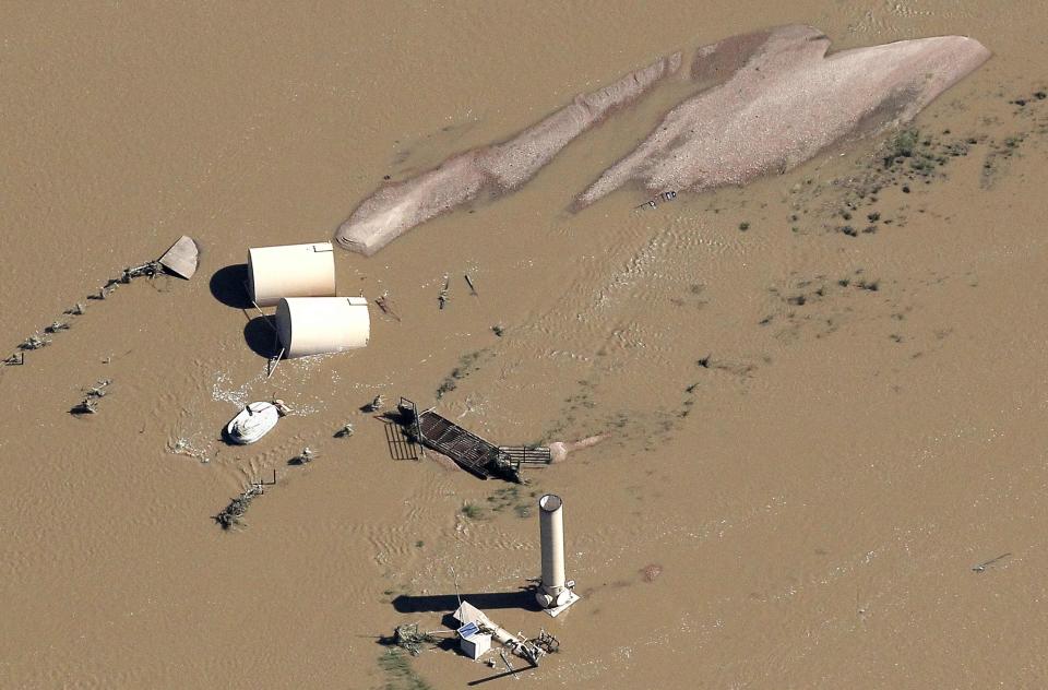 Oil storage tanks on a well pad lies toppled by flood waters in Weld County, Colorado