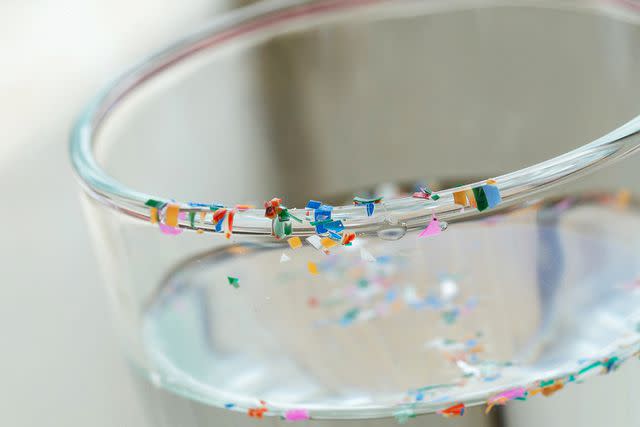 <p>pcess609/Getty</p> Microplastics on water glass.