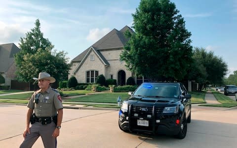 A police officer stands outside a home in Allen, Texas, believed to be associated with a mass shooting  - Credit: AP