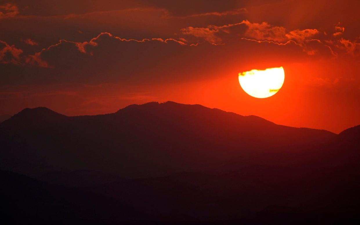 The sun sets behind the Rocky Mountains and turns the sky red as wildfires burn across the state of Colorado last month. Fires and high temperatures are thought to have disrupted the migration of thousands of birds - David Zalubowski /AP