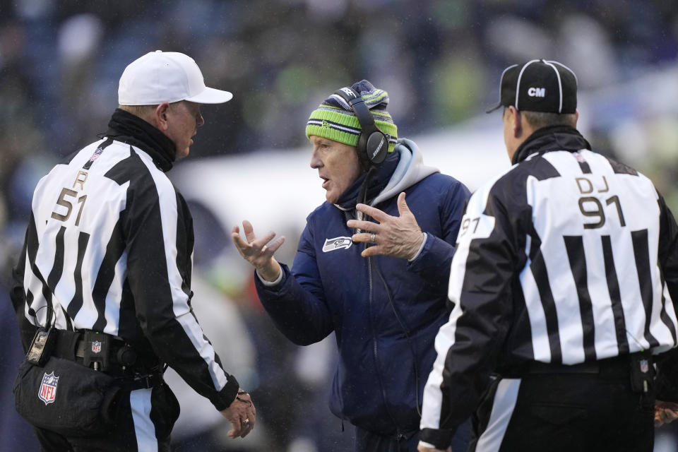 Seattle Seahawks head coach Pete Carroll, center, talks with officials during the second half of an NFL football game against the Chicago Bears, Sunday, Dec. 26, 2021, in Seattle. (AP Photo/Stephen Brashear)