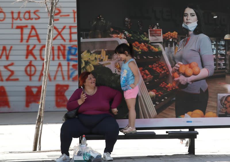 A woman and a child wait for a bus at Syntagma Square following the coronavirus disease (COVID-19) outbreak in Athens