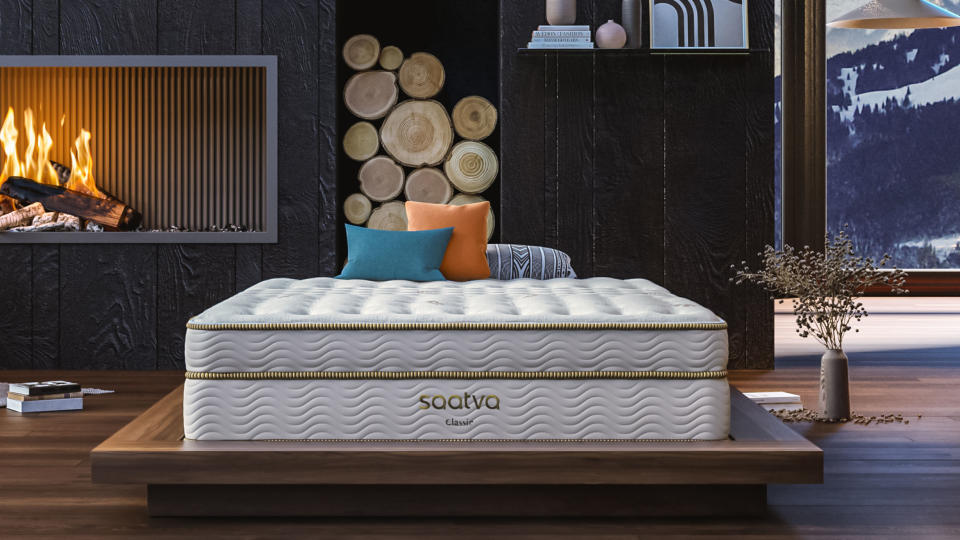 Image shows the Saatva Classic mattress on a wooden bed frame in a luxury bedroom overlooking a snow-capped mountain