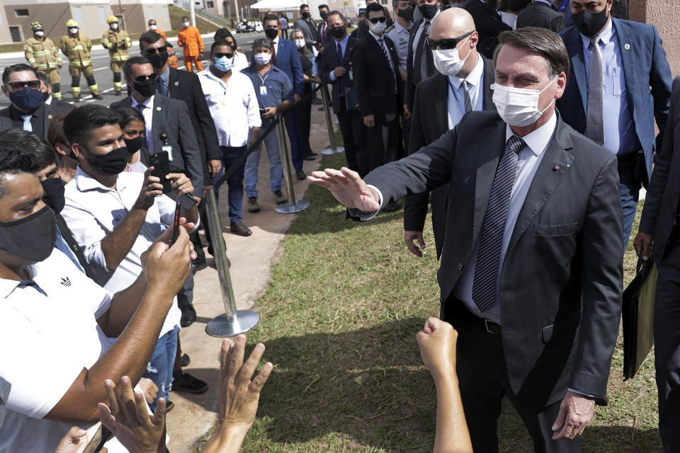 Wearing a mask to curb the spread of the new coronavirus, Brazil's President Jair Bolsonaro greets people after a ceremony to deliver affordable homes built by the government, in a neighborhood of Brasilia, Brazil, Monday, Apr. 5, 2021. (AP Photo/Eraldo Peres)