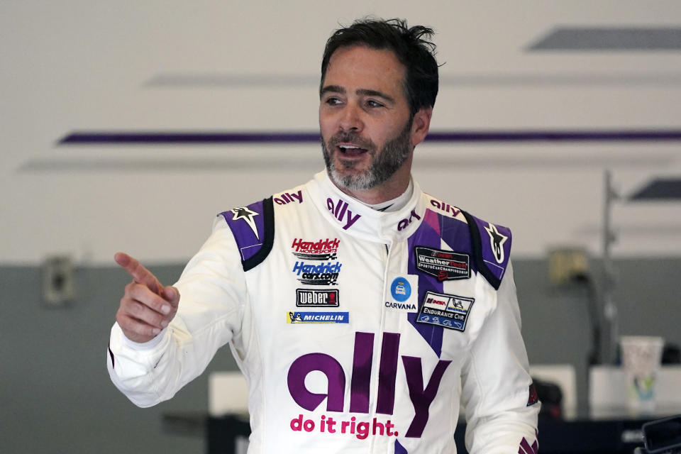 Jimmie Johnson interacts with crew members in his garage during a practice session for the Rolex 24 hour auto race at Daytona International Speedway, Saturday, Jan. 23, 2021, in Daytona Beach, Fla. (AP Photo/John Raoux)