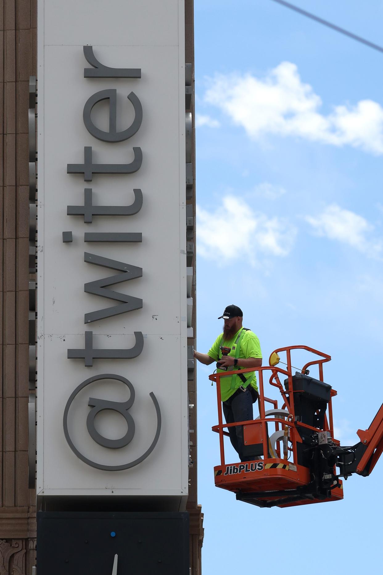 A worker removes letters from the Twitter sign that is posted on the exterior of Twitter headquarters on July 24 in San Francisco.