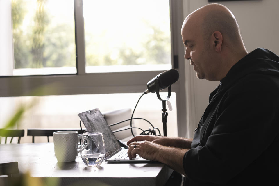 Emmy Award-winning producer Johnathan Walton works at his laptop inside his apartment in downtown Los Angeles, Monday, March 25, 2024. Walton was scammed by con artist Marianne "Mair" Smyth, who is now facing extradition to the United Kingdom. Walton started a podcast in 2021, “Queen of the Con,” to warn others about Smyth after he said he was fleeced out of nearly $100,000. (AP Photo/Damian Dovarganes)