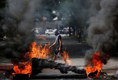 A demonstrator walks behind a fire barricade while participating in a strike called to protest against Venezuelan President Nicolas Maduro's government in Caracas. REUTERS/Carlos Garcia Rawlins