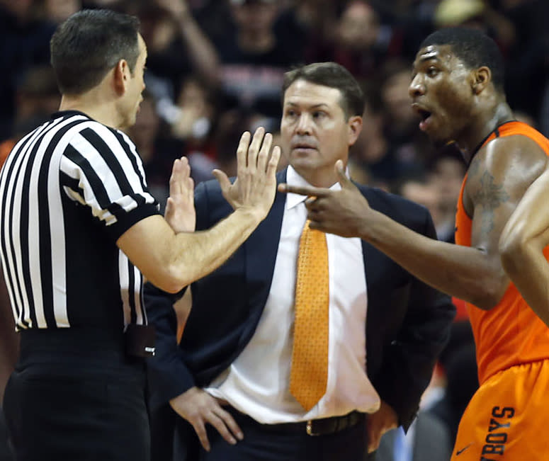 Oklahoma State head coach Travis Ford, center, Marcus Smart and Markel Brown, right, talk to the referee after Smart shoved a fan during an NCAA college basketball game against Texas Tech, Saturday, Feb, 8, 2014, in Lubbock, Texas. (AP Photo/Lubbock Avalanche-Journal, Tori Eichberger) ALL LOCAL TV OUT.