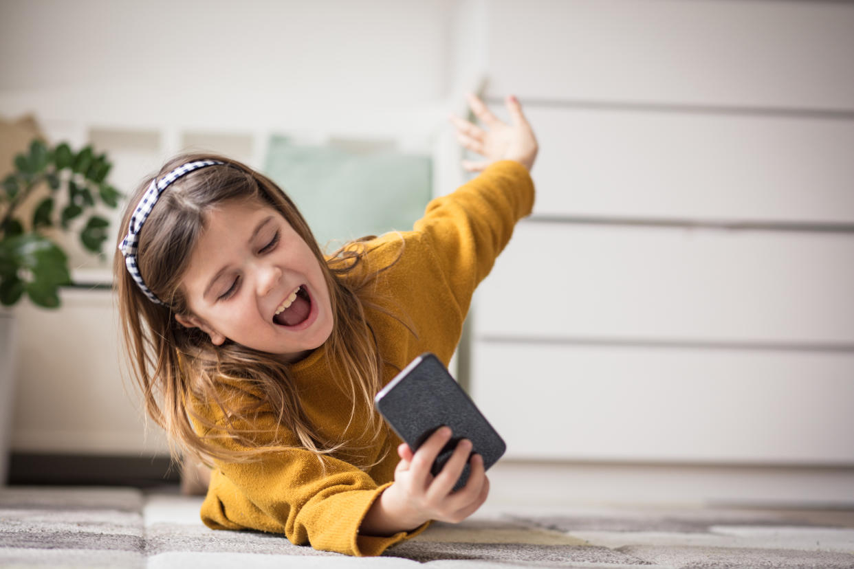 Happy to be able to talk to friends from afar. Little girl using smart phone.