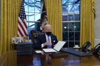 President Joe Biden signs his first executive orders in the Oval Office of the White House on Wednesday, Jan. 20, 2021, in Washington. (AP Photo/Evan Vucci)