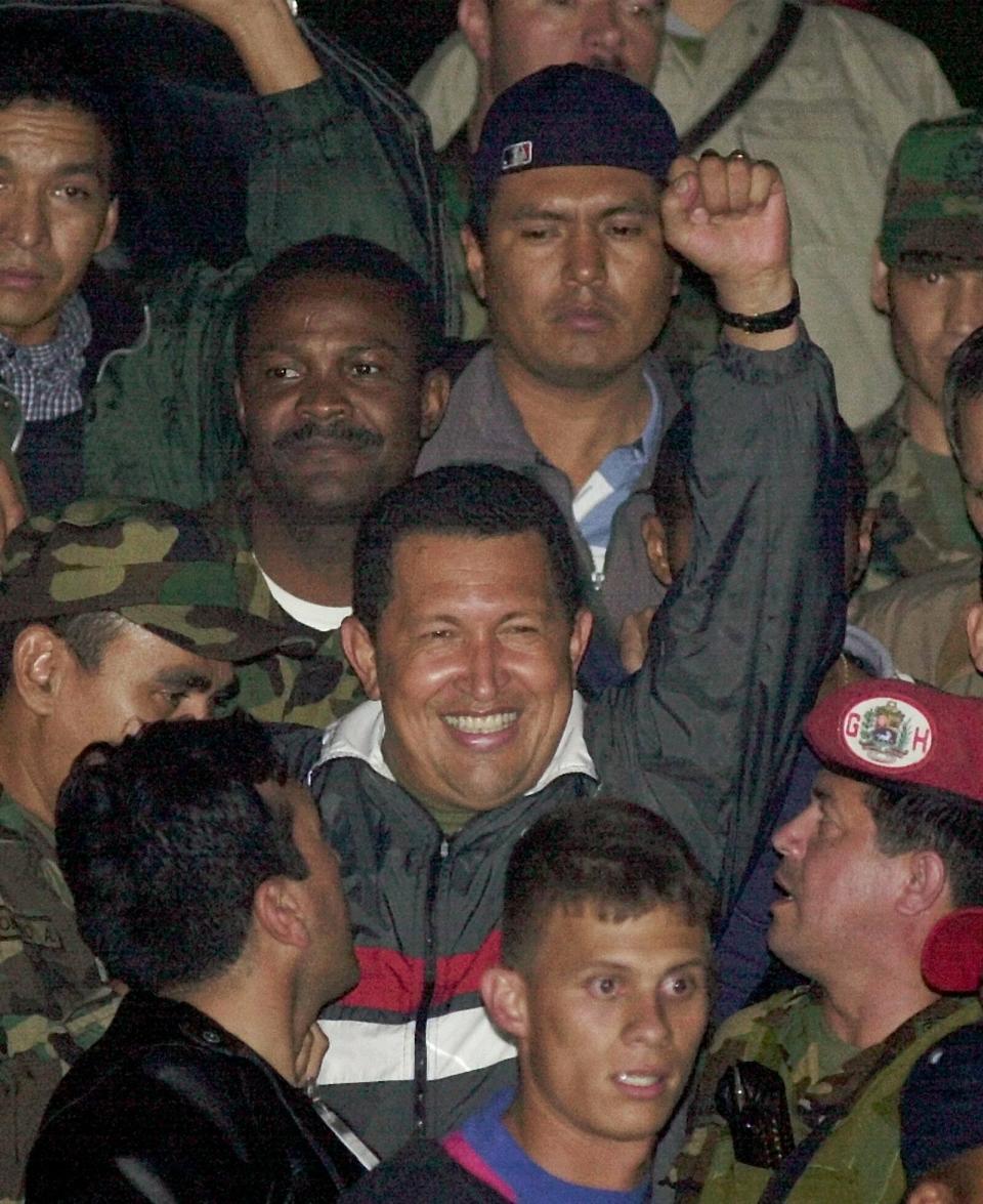 FILE - In this April 14, 2002 file photo, Venezuela's President Hugo Chavez gestures to supporters as he arrives to Miraflores presidential palace after being freed by his military captors two days after the military announced he had resigned in Caracas, Venezuela. Chavez was ousted for two days before retaking power. He and his allies accuse the U.S. of tacit support for the coup attempt. (AP Photo/Dario Lopez-Mills, File)