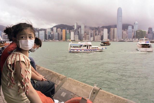 A girl wearing a mask to ward off SARS sits along the harbourside viewing the skyline of Hong Kong, on May 17, 2013. SARS was followed by the 2009-2010 H1N1 "swine flu" pandemic, which scientists said infected more than a fifth of the world's people and may have killed as many as 250,000 -- about the yearly seasonal flu toll