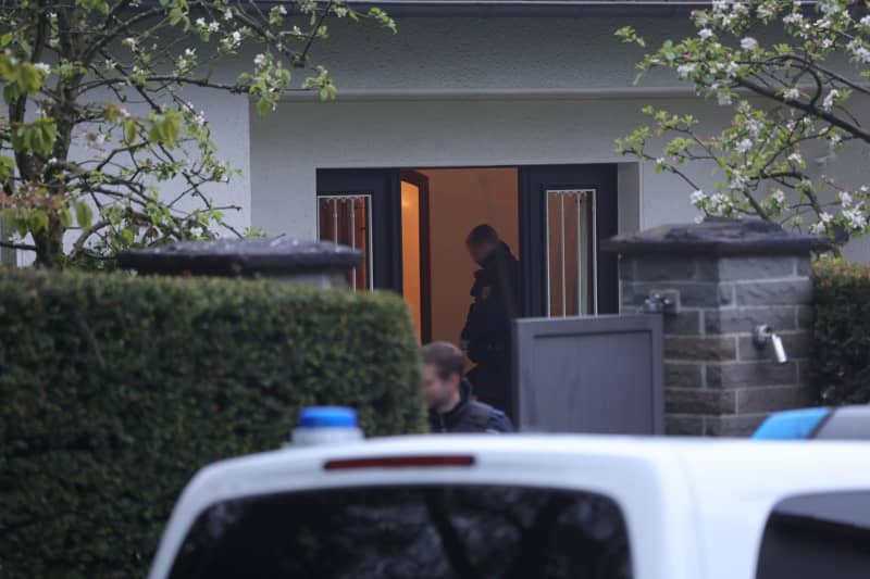 Police officers stand outside a house being searched during a massive raid against an international smuggling ring in eight states.  Gianni Gattus/dpa