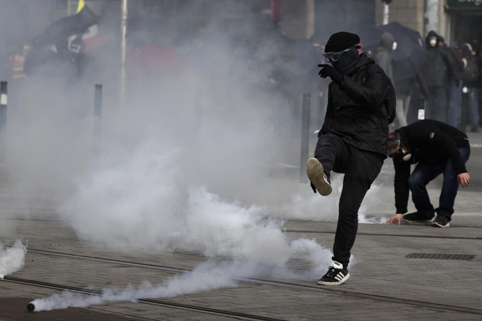 Youth kicks in a tear gas canisters during a demonstration Tuesday, March 7, 2023 in Nantes, western France. Garbage collectors, utility workers and train drivers are among people walking off the job across France to show their anger at a bill raising the retirement age to 64, which unions see as a broader threat to the French social model. (Jeremias Gonzalez)