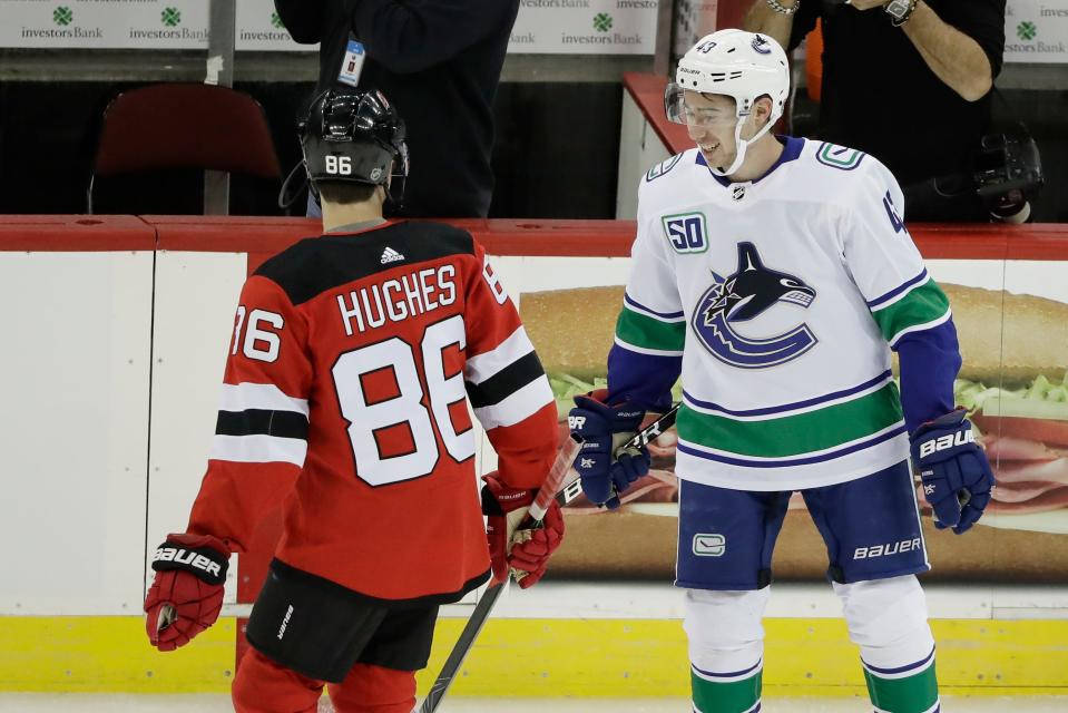 FILE - Vancouver Canucks' Quinn Hughes, right, talks to his brother, New Jersey Devils' Jack Hughes, left, before of a game Saturday, Oct. 19, 2019, in Newark, N.J. (AP Photo/Frank Franklin II, File)