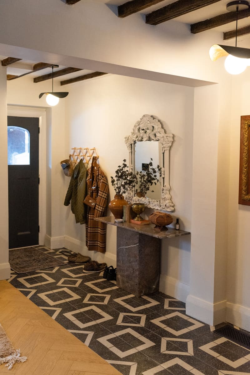 Clothes hung up in an entryway next to a stone table.